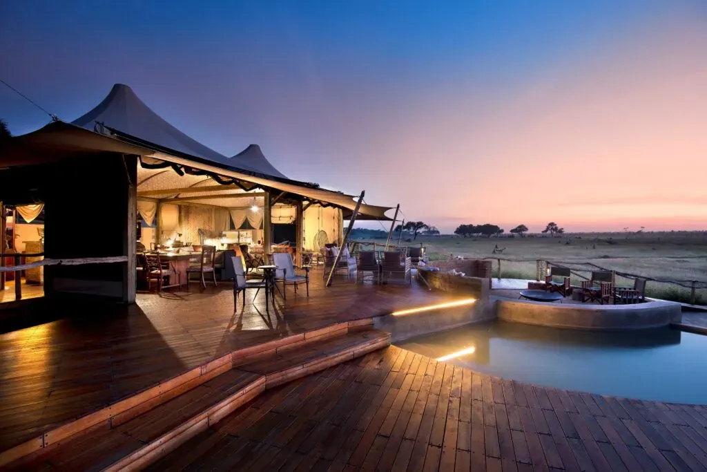 Somalisa Camp at dusk with warmly lit tents and a circular pool reflecting the twilight sky