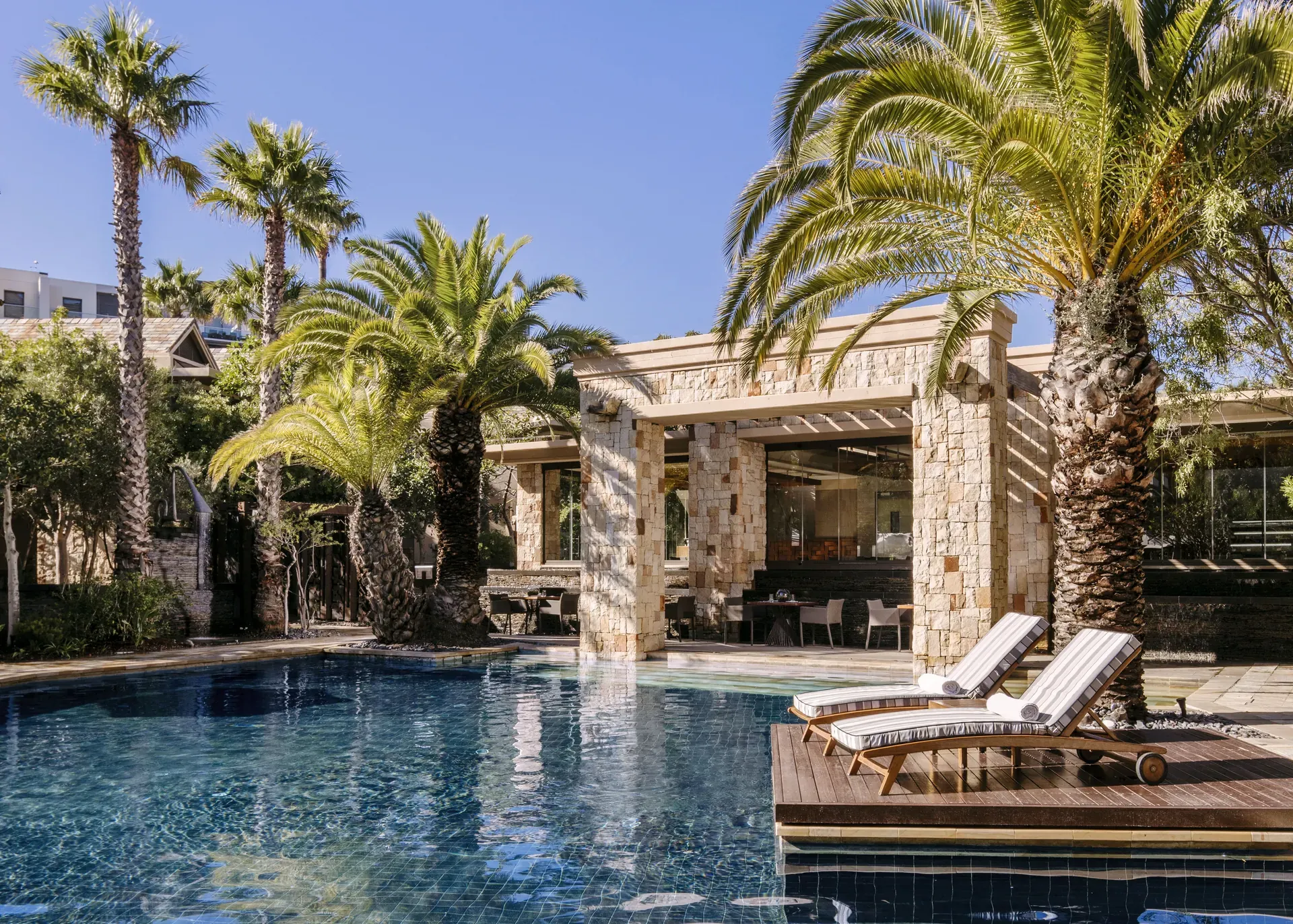 Isola outdoor restaurant at Cape Town with stone architecture, palm trees and poolside seating