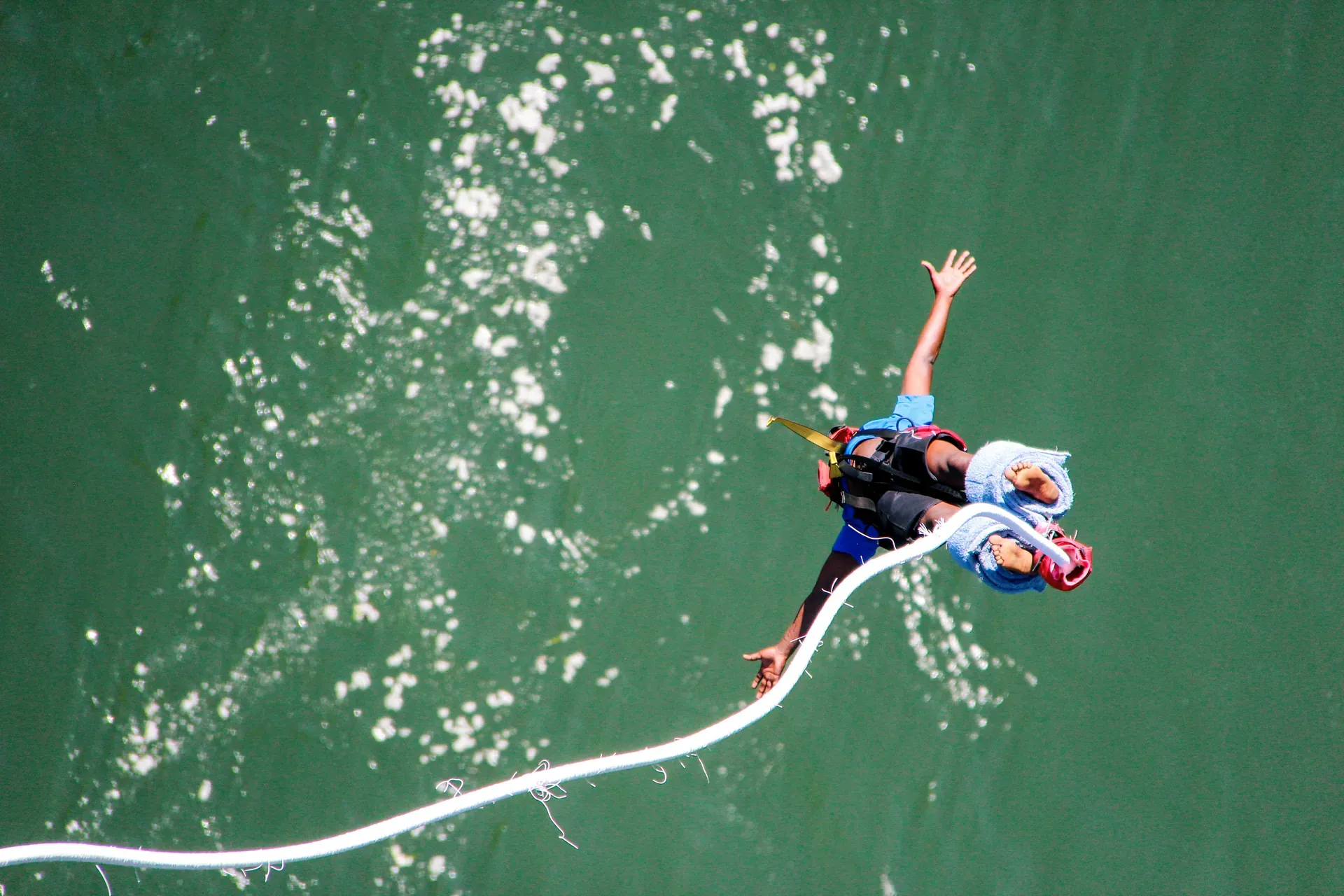 Adventurer ziplining across a turquoise river on a harness for a thrilling experience
