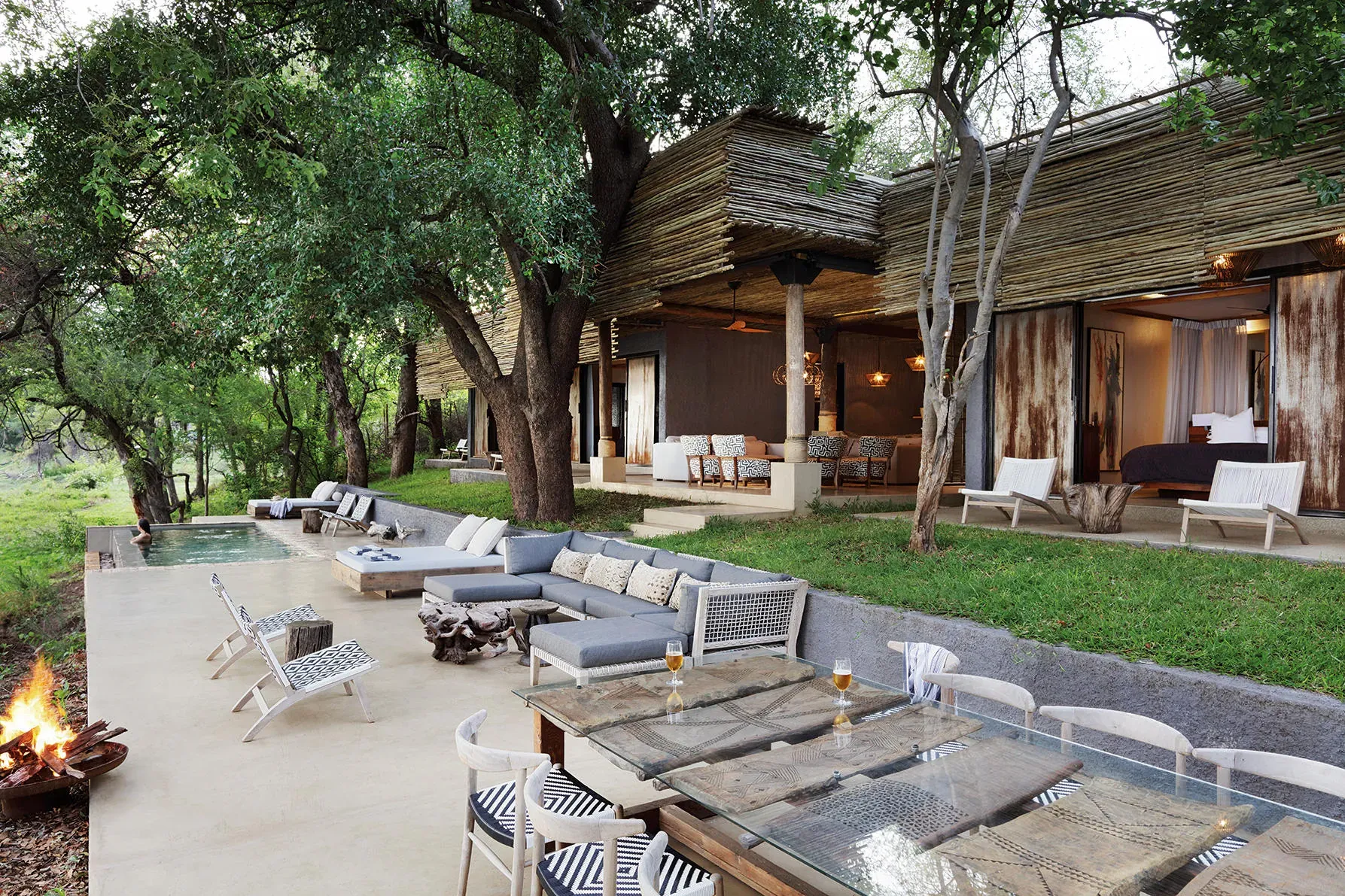Matetsi Victoria Falls lodge with rustic red-walled buildings and a serene courtyard pool surrounded by trees
