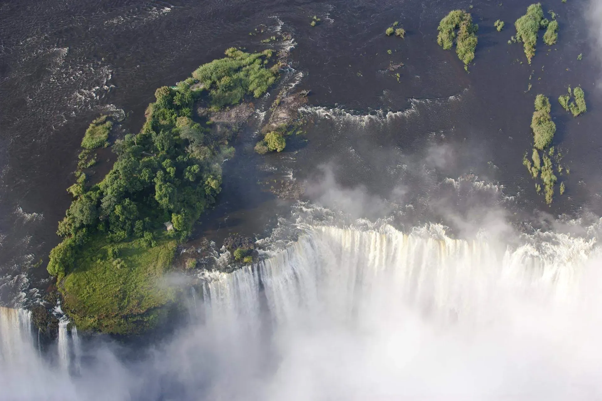 Aerial view of Victoria Falls from the Zambian side with powerful white water cascading into the gorge amid lush green cliffs